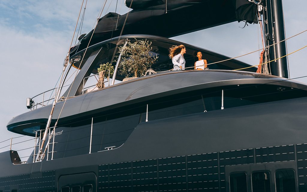 Catamarán de vela Sunreef 80 con dos mujeres en la cubierta superior junto a un olivo en maceta