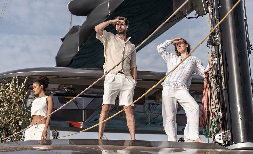 Tres personas protegiéndose los ojos del sol en la cubierta de un catamarán de vela