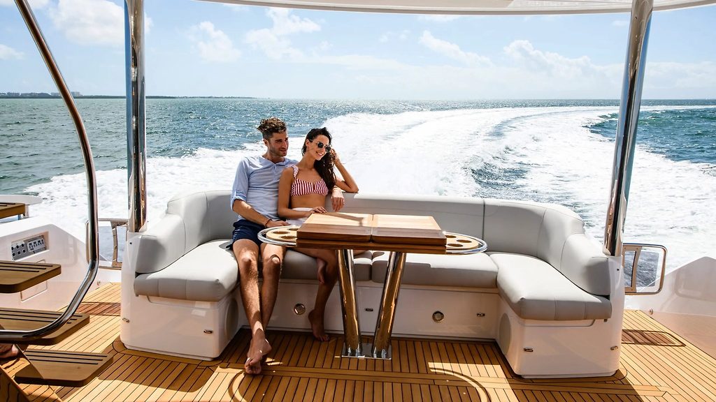 Paar entspannt auf der Achterdecksitzgruppe einer fahrenden Motoryacht auf See