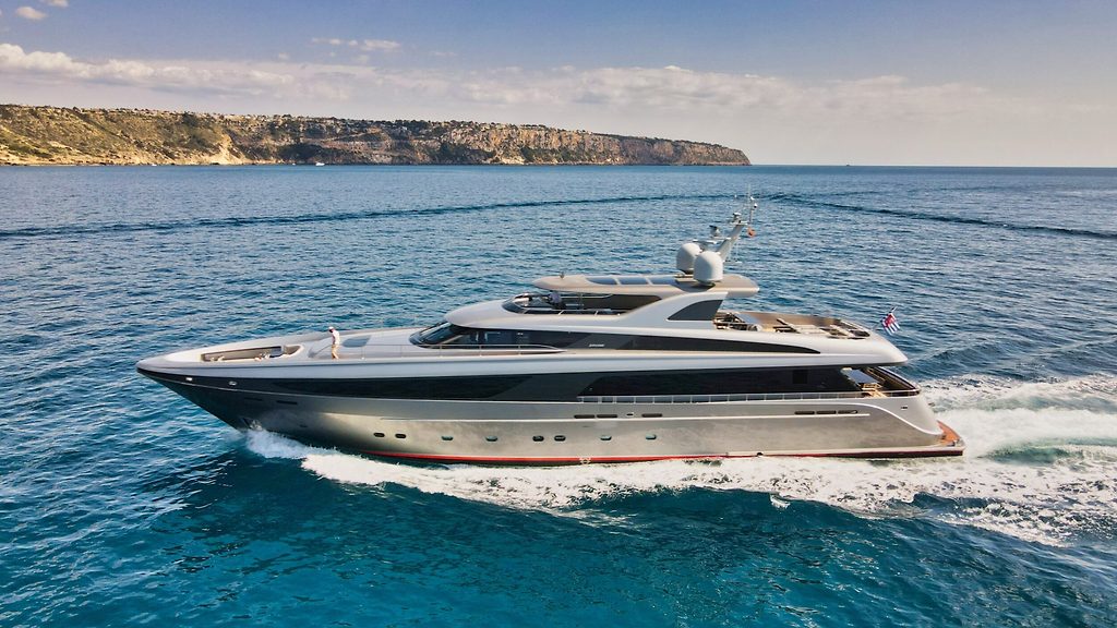 Motor yacht cruising near a coastal cliff, seen from the side