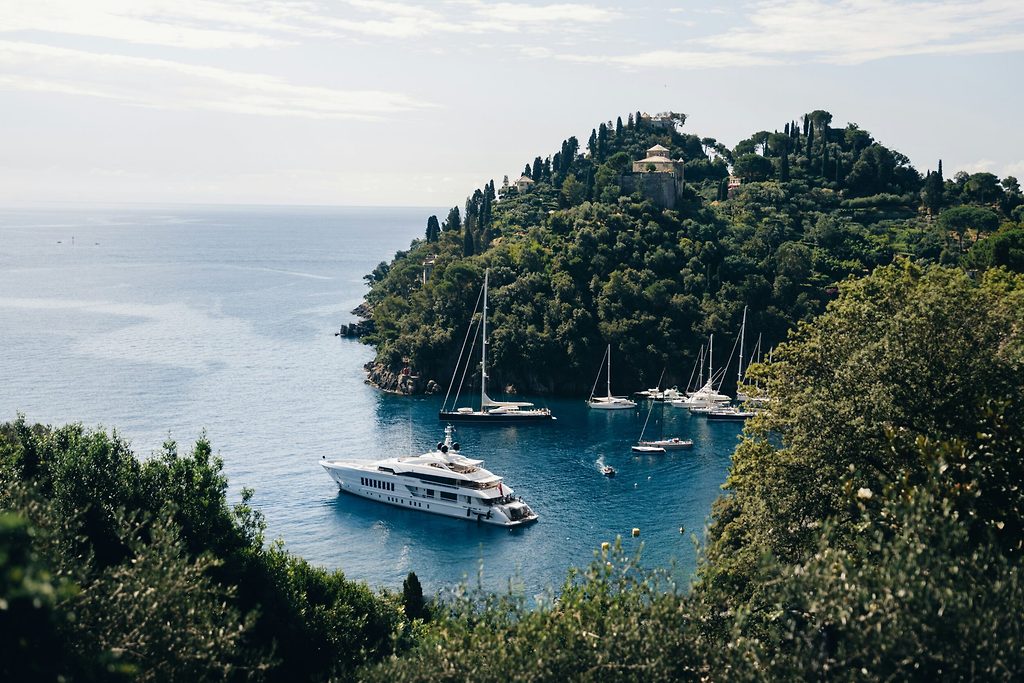 Yacht à moteur et voiliers ancrés dans une crique boisée sur la côte méditerranéenne