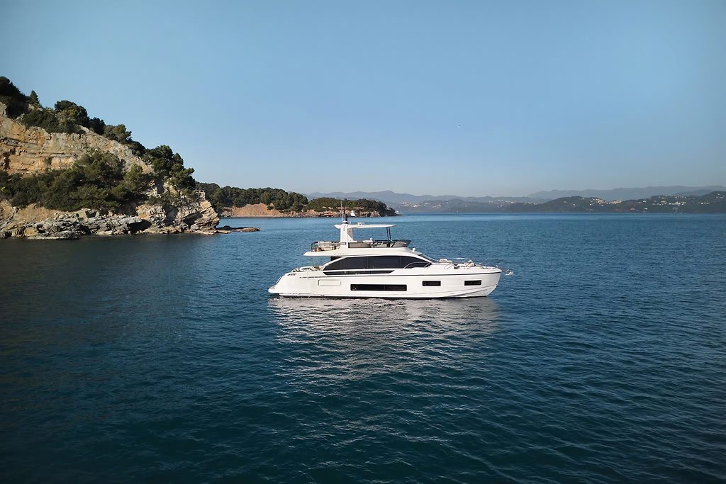 Yacht à moteur au mouillage près d'une côte rocheuse, mer ouverte à l'arrière-plan
