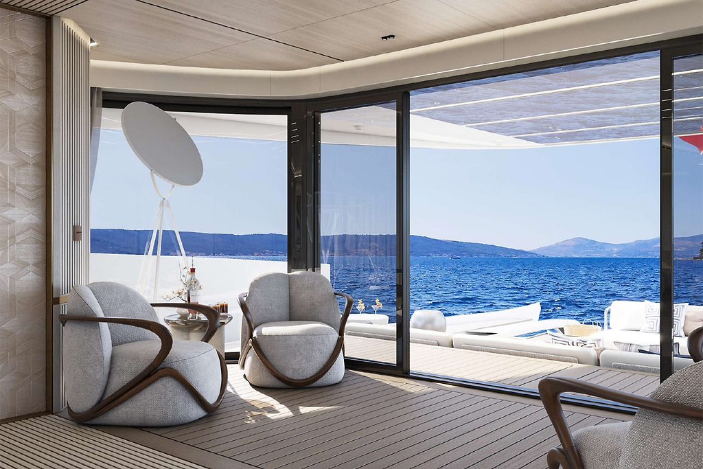 Lounge seating area on a yacht's deck with sliding glass doors open to the sea and hills