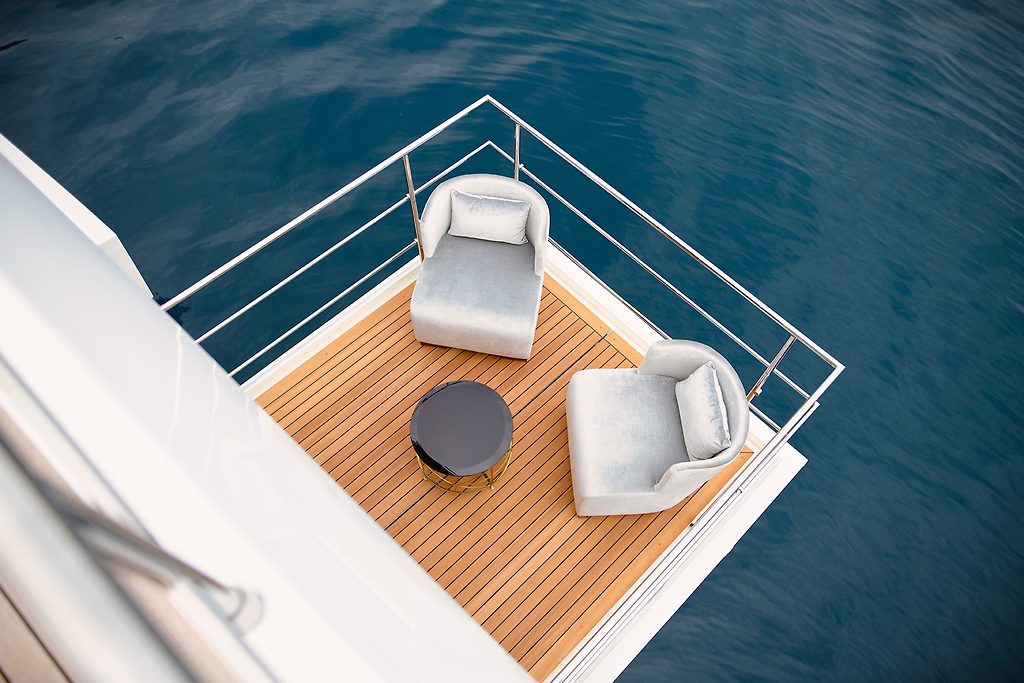 Bow lounge deck with two armchairs and a table on a yacht, seen from above, at sea