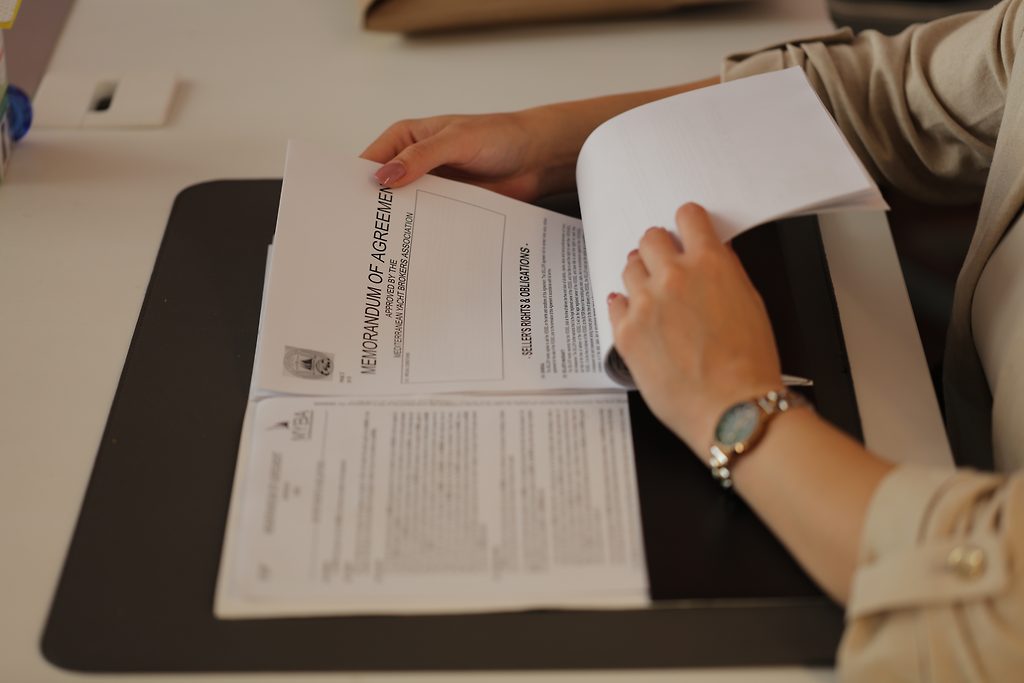 Memorandum of Agreement document with hands turning its pages on a desk