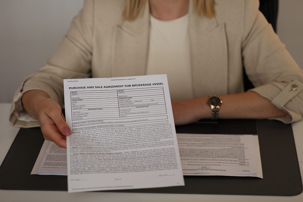 Courtière tendant un contrat d'achat et de vente pour un bateau de brokerage par-dessus un bureau