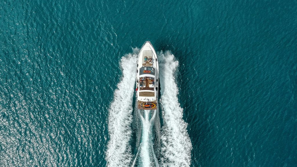 Vista aérea de un yate a motor navegando a gran velocidad, dejando una estela blanca en mar abierto