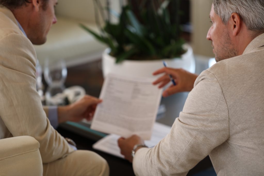Zwei Männer besprechen ein Dokument an einem Tisch im Innenbereich