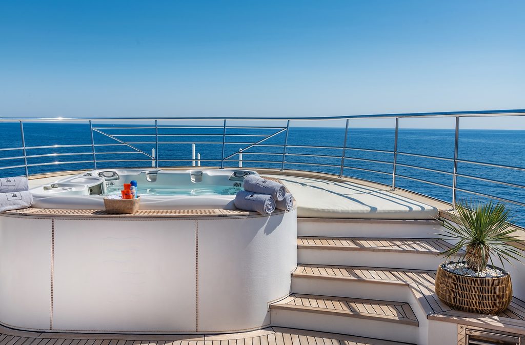 Whirlpool mit gerollten Handtüchern auf dem Sonnendeck einer Yacht, Meer im Hintergrund