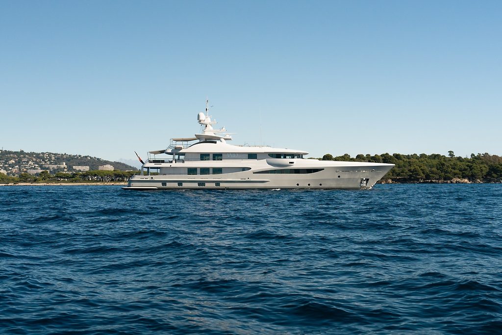 Yacht à moteur naviguant le long d'une côte aux collines boisées