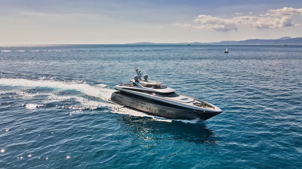 Motoryacht fährt mit Fahrt über offene See, Küste im Hintergrund