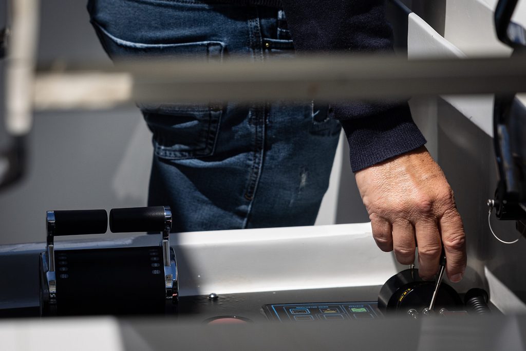 Hand resting on the throttle control at a yacht's helm station