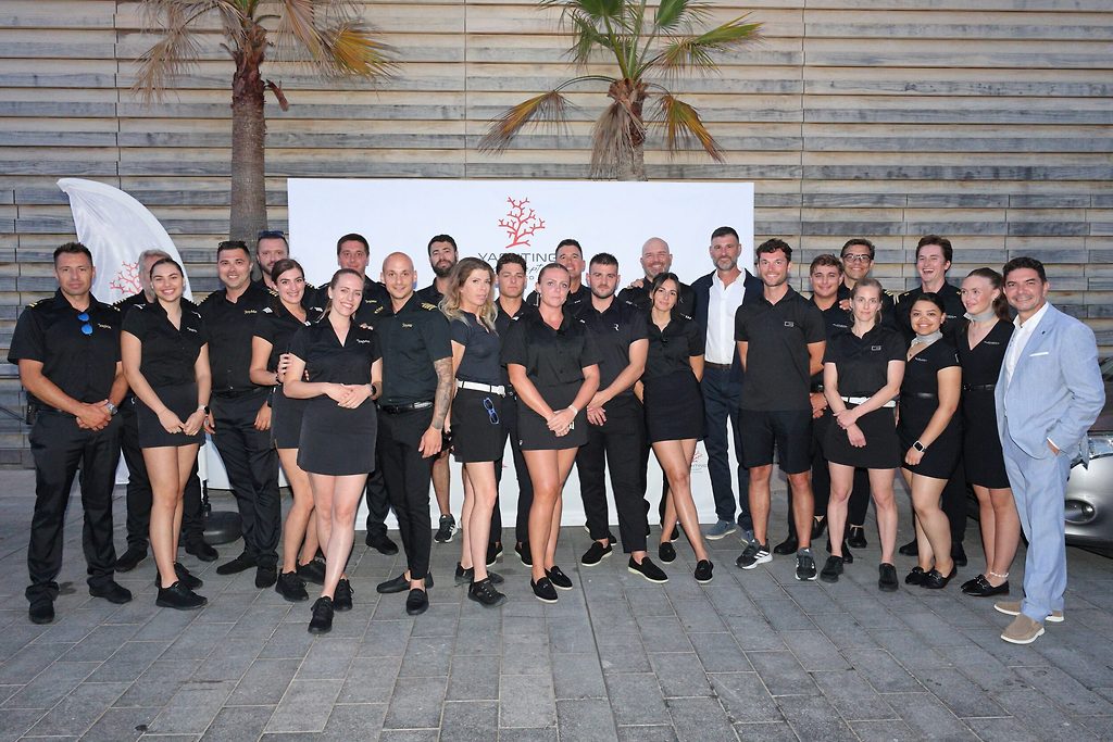 Group of yacht crew members in uniform posing together at an outdoor event