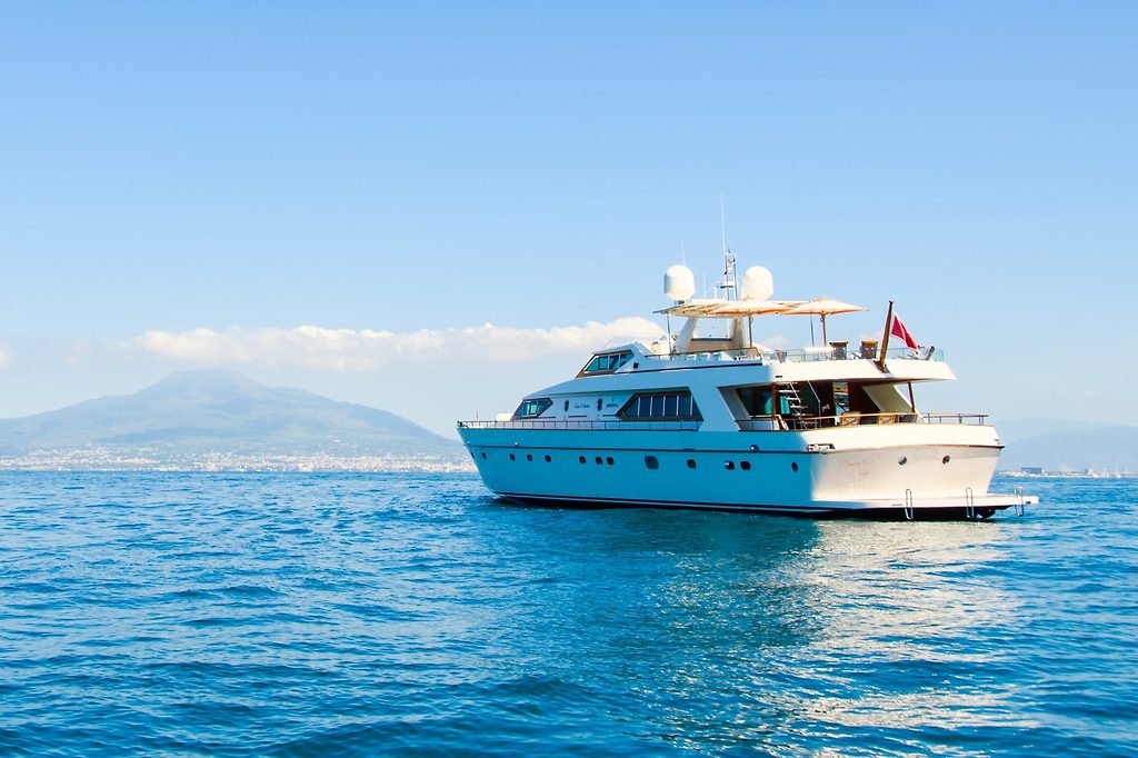 Motoryacht vor Anker im offenen Wasser, im Hintergrund eine bergige Küste