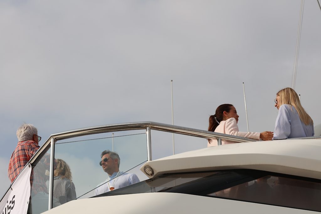 Visitors standing on the flybridge of a motor yacht, talking near the railing