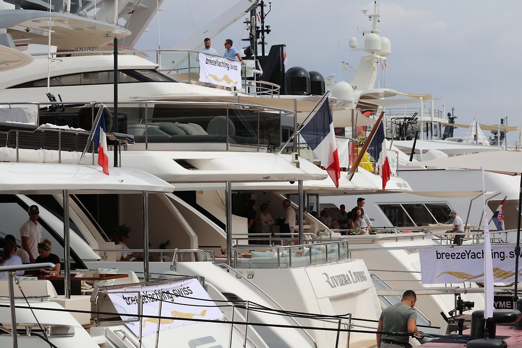 Motor yachts moored side by side with breezeYachting.swiss banners at a boat show