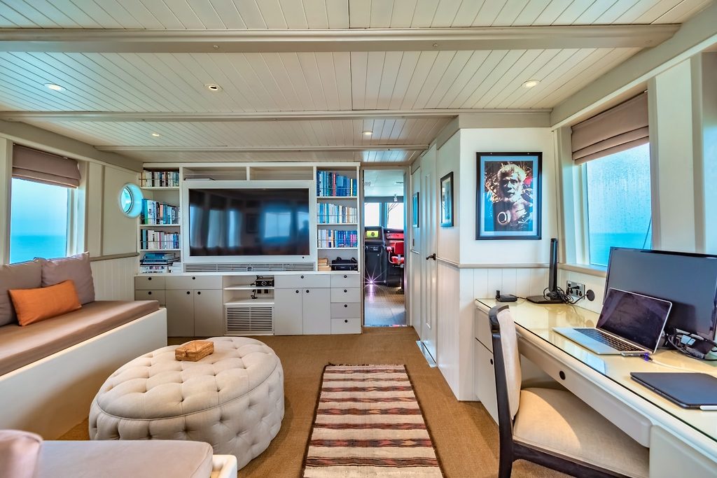 Salon einer Motoryacht mit Sofa, Bücherregalen, Fernseher und Schreibtischbereich