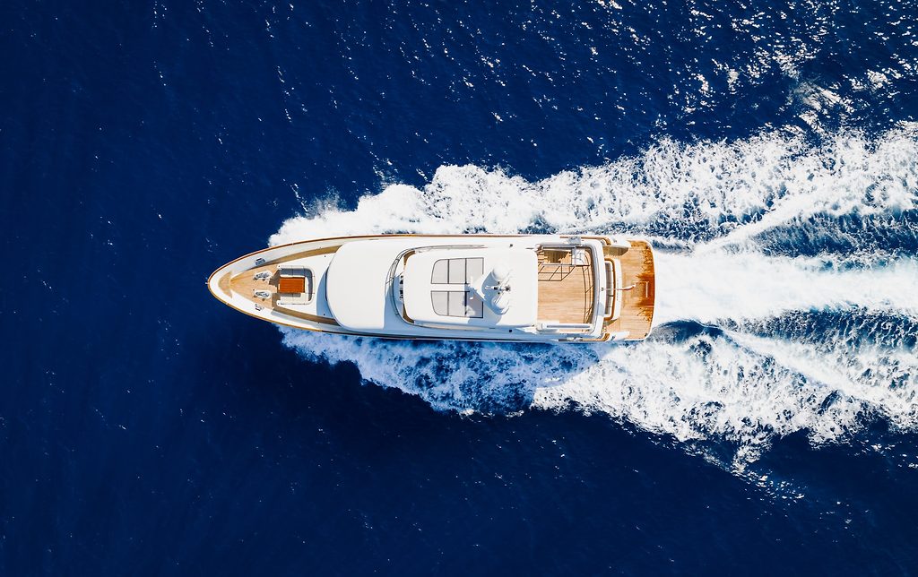 Luftaufnahme einer Motoryacht bei voller Fahrt mit breitem Kielwasser auf offener See