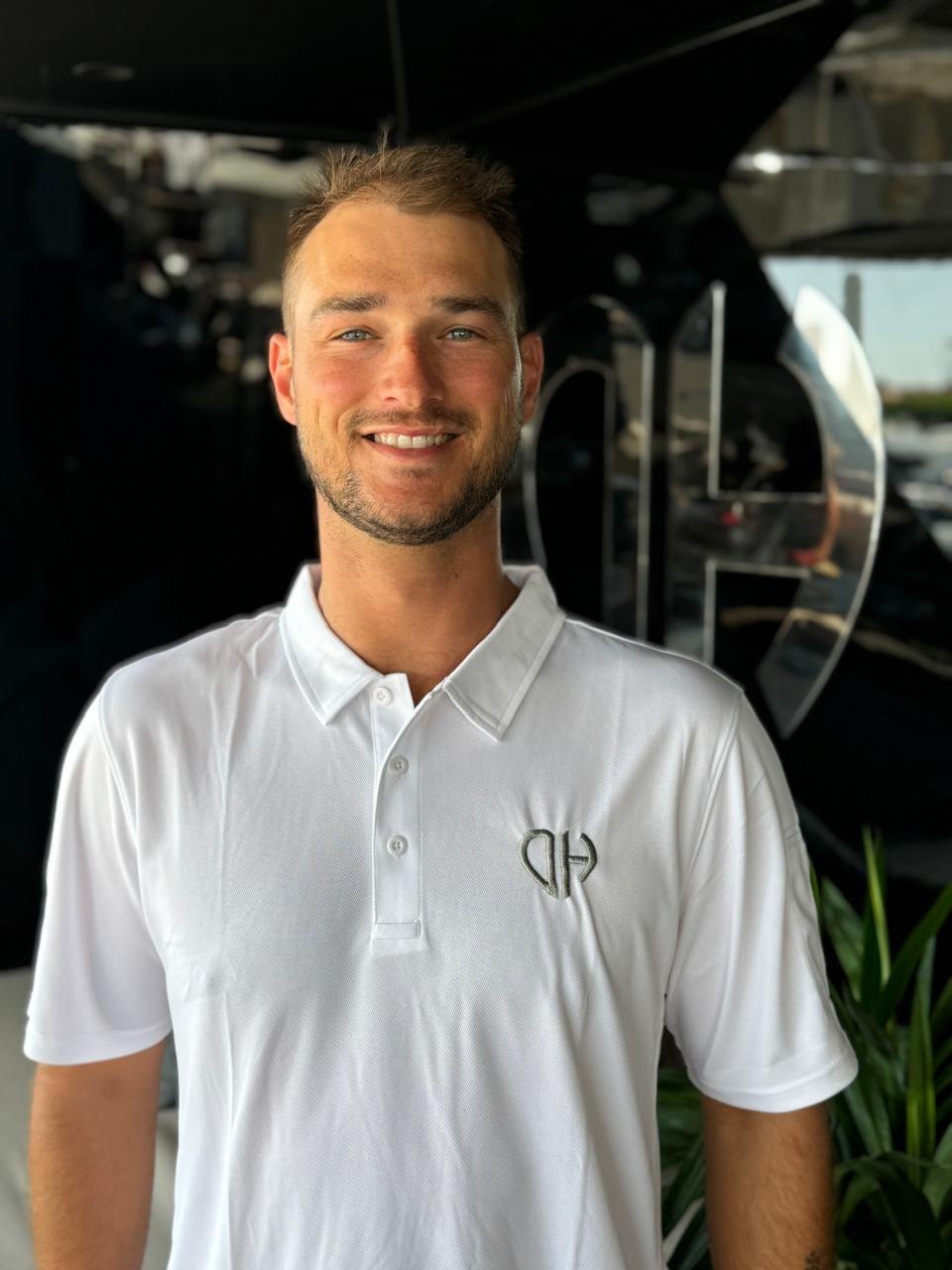 Crewmitglied im weissen Poloshirt lächelt an Bord einer Yacht