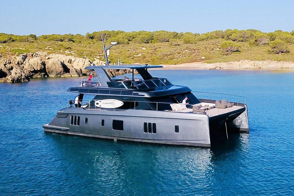 Catamaran à moteur ancré dans une baie rocheuse près de la côte