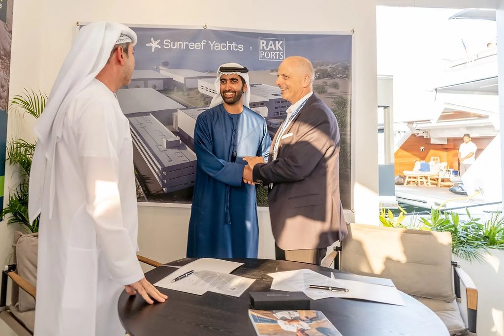 Hombres dándose la mano en una ceremonia de firma frente a una pancarta de Sunreef Yachts y RAK Ports