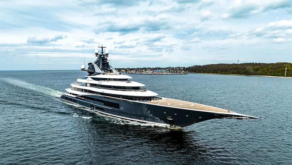Superyacht avec pont d'hélicoptère naviguant près d'une côte