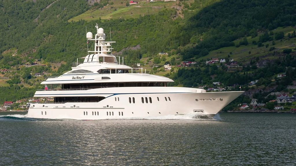 Superyacht naviguant sur un fjord, versants boisés en arrière-plan