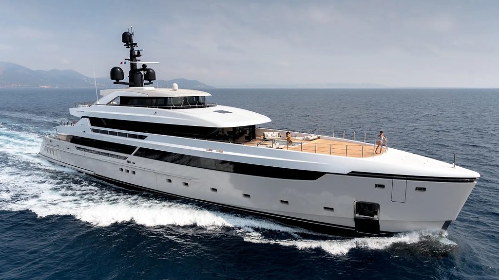 Superyacht naviguant à vitesse en mer ouverte, avec des personnes détendues sur le pont avant