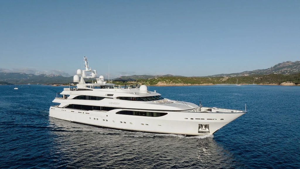 Superyacht naviguant près d'une côte vallonnée sous un ciel dégagé