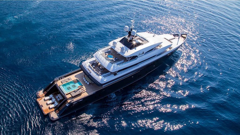 Vue aérienne d'un yacht à moteur avec piscine sur le pont arrière, naviguant en mer ouverte