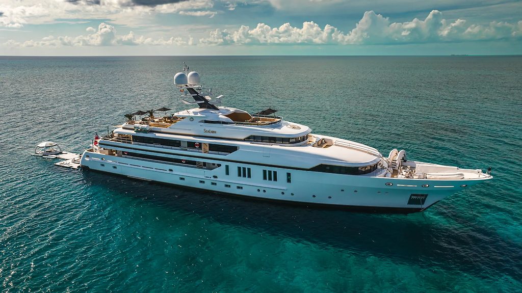Superyacht au mouillage dans une eau turquoise, avec une annexe à ses côtés