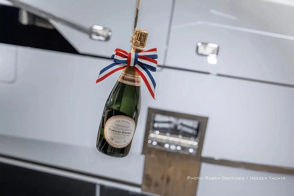 Bouteille de champagne ornée d'un ruban suspendue pour une cérémonie de baptême sur la coque d'un yacht
