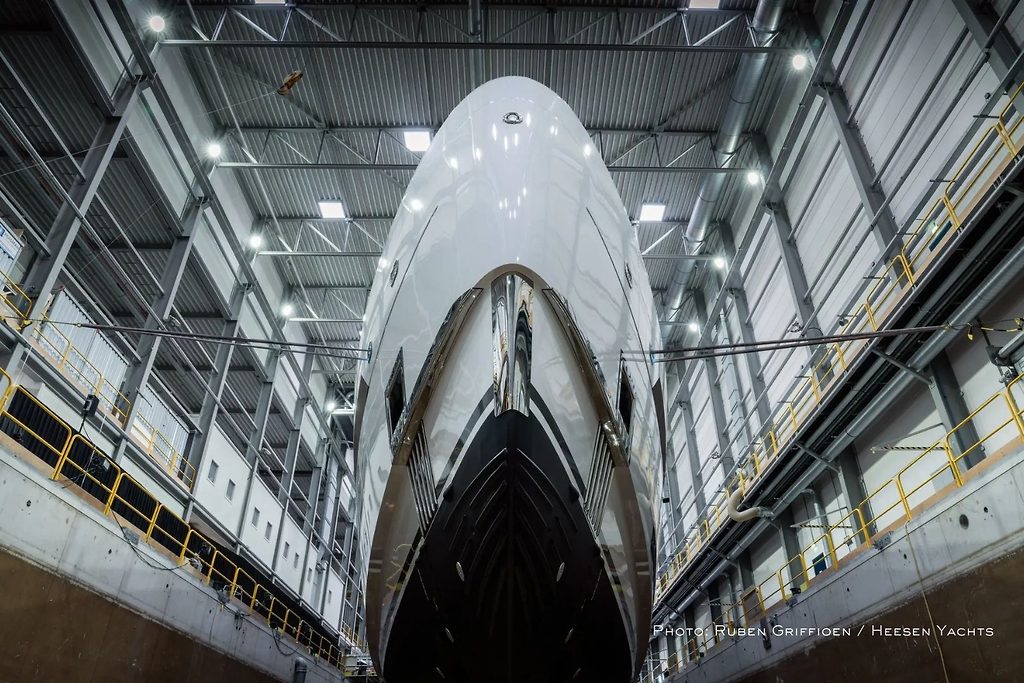 Vista de proa del casco de un superyate en construcción dentro de un hangar de astillero