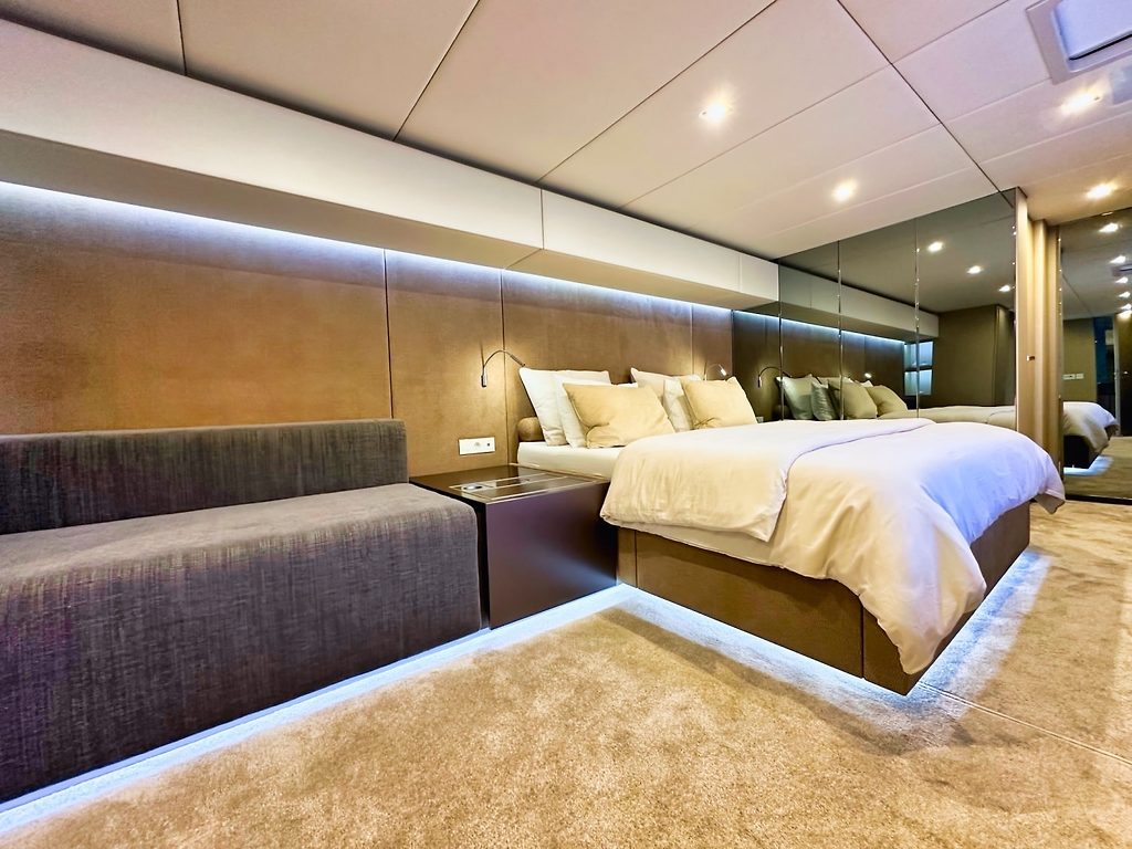Camarote principal con cama doble y sofá a bordo de un yate, iluminación LED ambiental