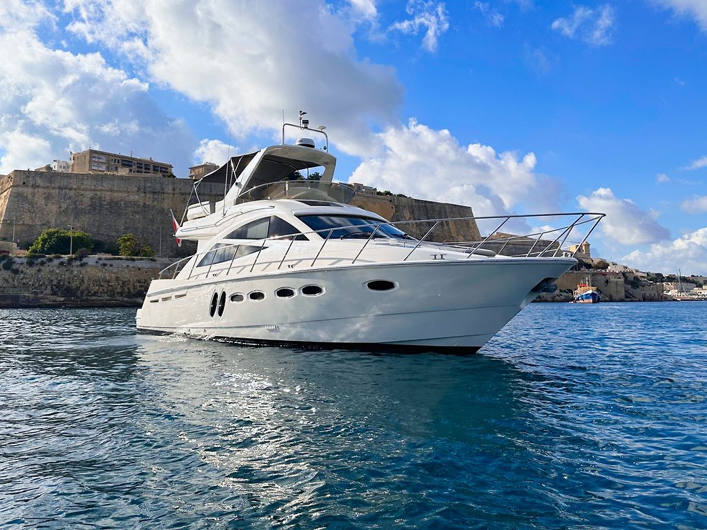 Моторная яхта Sealine T50 у укреплённого побережья под небом с редкими облаками