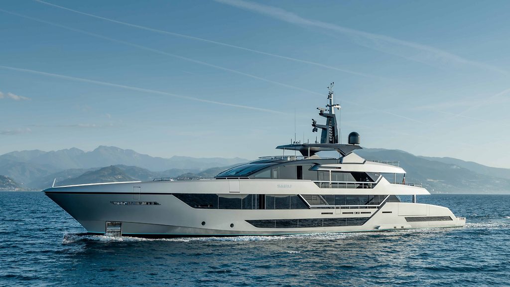 Motor yacht cruising on open water with mountains in the background