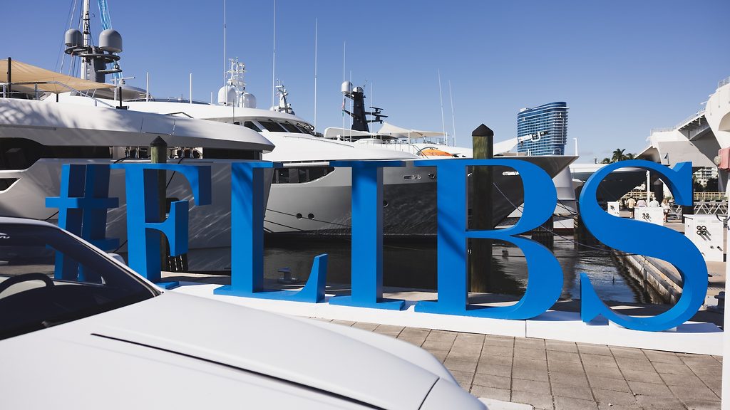 #FLIBS sign at the boat show marina, superyachts docked behind