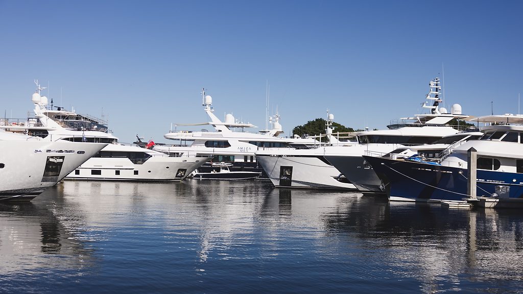 Row of motor yachts moored stern-to at a marina under a clear sky
