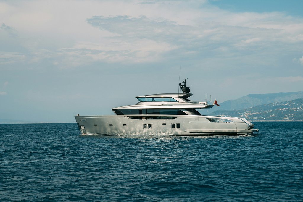 Yacht a motore in navigazione in mare aperto, costa montuosa sullo sfondo