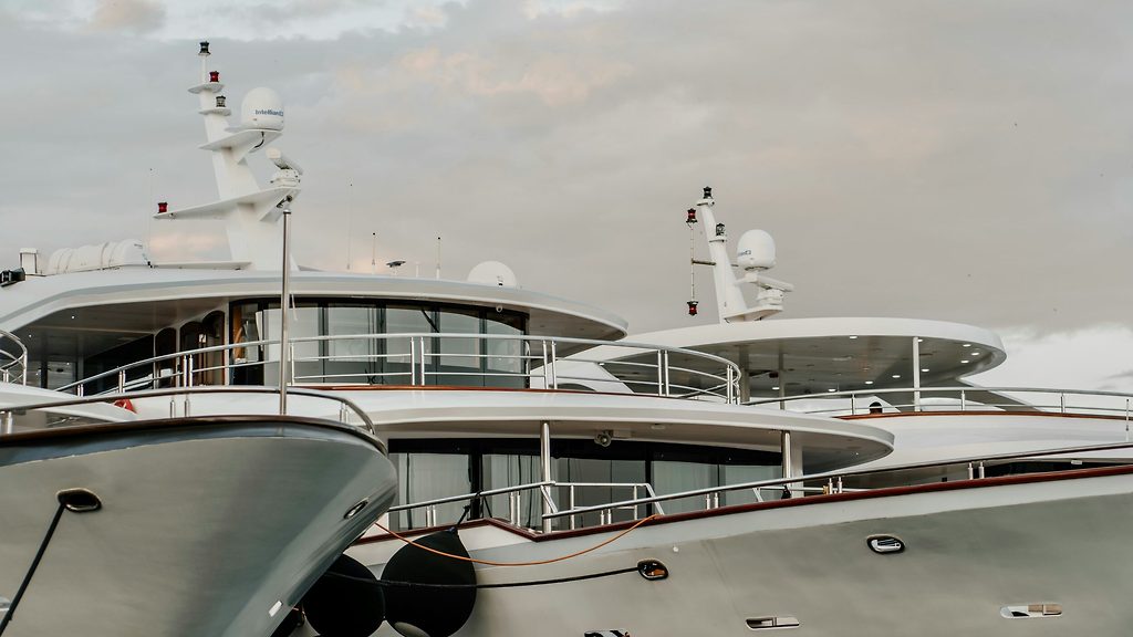 Superyacht ormeggiati fianco a fianco, prue e ponti superiori con alberi radar, cielo coperto