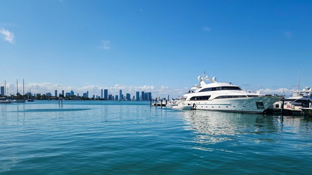 Motor yacht docked at a marina, city skyline across the water